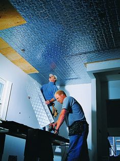 two men working on a ceiling in a room