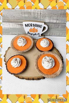 four cupcakes with whipped cream on top are sitting on a wood slab and the words morning pumpkin is above them