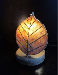 a lamp that is sitting on top of a wooden stand with a leaf shaped light