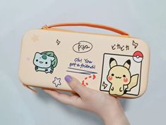 a hand holding a pokemon wallet with pictures on it