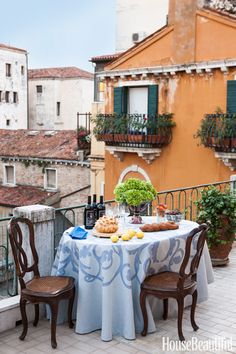 an outdoor table with food on it in front of a balcony overlooking the cityscape