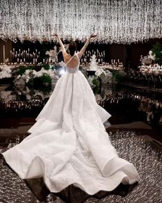 a woman in a white wedding dress standing on top of a table with chandelier