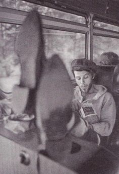 black and white photograph of people sitting on a bus looking at a book in their hands