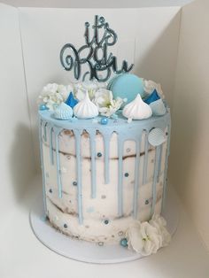 a blue and white cake decorated with seashells, flowers and the word it's ocean on top