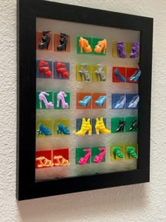 an art piece is hanging on the wall with different colored shoes in it's shadow