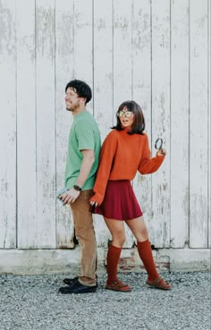 a man and woman standing next to each other in front of a white wall with wooden planks