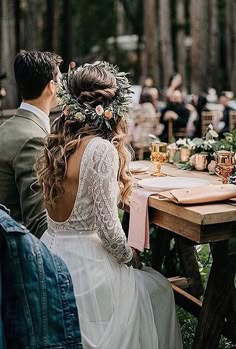 a man and woman sitting at a table with flowers in their hair, surrounded by other people