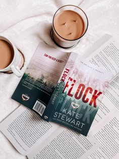 there is a cup of coffee and a book on the bed next to each other