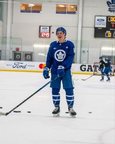 an ice hockey player is standing on the ice with his stick in hand and smiling