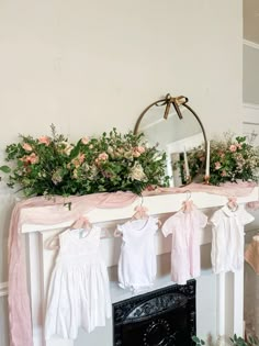 a mantle with flowers and baby clothes hanging from it