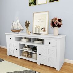 a white entertainment center with two pictures on the wall