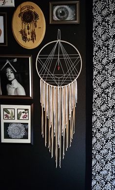 a black wall with pictures on it and a white dream catcher hanging from the wall