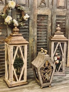 two decorative lanterns sitting next to each other on a wooden floor in front of shutters