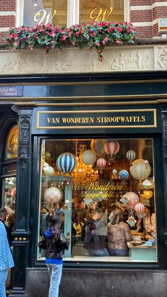 a store front with many balloons in the window and people walking around outside on the sidewalk