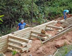 two men work on building wooden benches in the woods