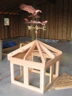 a small wooden structure with a weather vane on it's roof and an eagle figurine on top