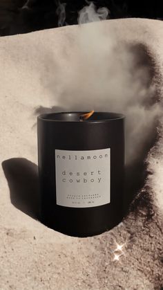 a black candle sitting on top of a snow covered ground with steam coming out of it