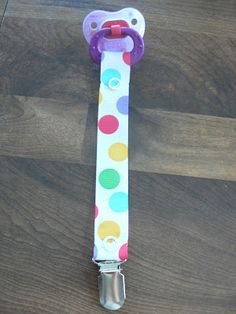 a colorful polka dot lanyard on a wooden floor with a metal clip attached to it