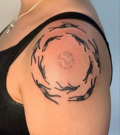 a woman with a tattoo on her shoulder that has fish in the middle of it