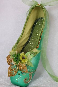 a close up of a shoe with flowers on the side and green ribbon around it