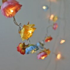 some lights that are hanging from a wire with flowers on it and one light is turned on