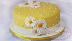 a yellow cake with white daisies on top