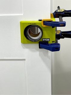 a yellow camera mounted to the side of a white door with blue and yellow handles