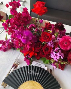 a bouquet of flowers sitting on top of a table next to an umbrella and fan