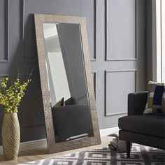 a large mirror sitting on top of a wooden floor next to a vase filled with flowers