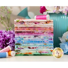 a stack of colorful fabric next to some flowers