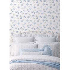 a bed with blue and white floral wallpaper next to a headboard in a bedroom