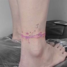 a woman's foot with a pink and purple tattoo on the left side of her ankle