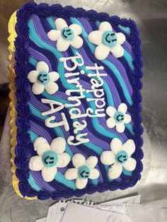 a purple and blue birthday cake with flowers on it