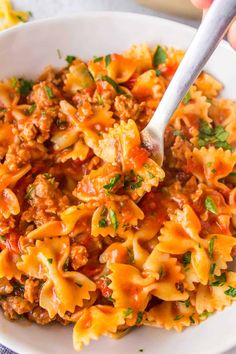 a white bowl filled with pasta and meat