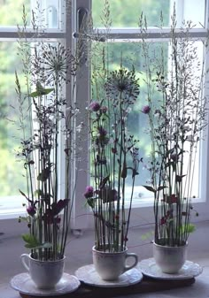 three vases filled with flowers sitting on top of a table next to a window