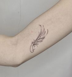 a woman's arm with a feather tattoo on the left side of her arm