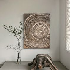 a living room with white walls and a large painting on the wall next to a tree stump