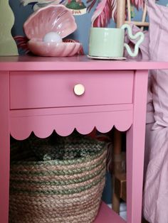 a pink table with a basket underneath it