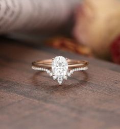 a close up view of a diamond ring on a wooden table with an apple in the background