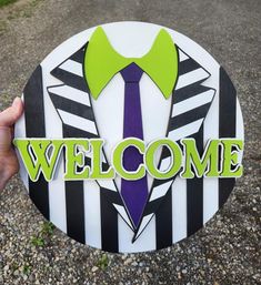 a hand holding up a welcome sign with a tie on it