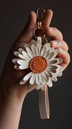 a hand holding a key chain with a flower on it