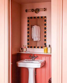 a bathroom sink sitting under a mirror next to a white toilet and pink walls with polka dots on it