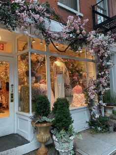 a store front with pink flowers in the window and mannequins on display