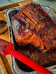 a large piece of meat sitting on top of a pan next to a spatula