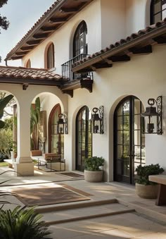 an outdoor patio with steps leading up to the front door and entry way, surrounded by potted plants