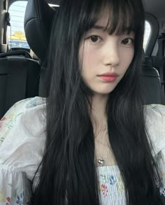 a woman with long black hair sitting in the back seat of a car looking at the camera