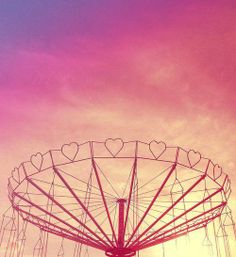 a ferris wheel with hearts on it against a pink sky