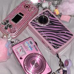 several different types of cell phones are laying on a white sheet with pink accessories around them