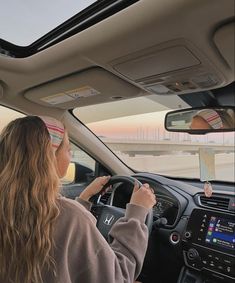 the woman is driving her car while looking at her cell phone