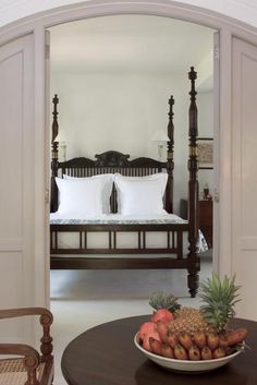 a bed sitting inside of a bedroom next to a table with fruit on top of it